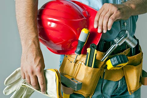 Man with red hard hat and tool belt covered by Contractors Insurance in Omaha, NE